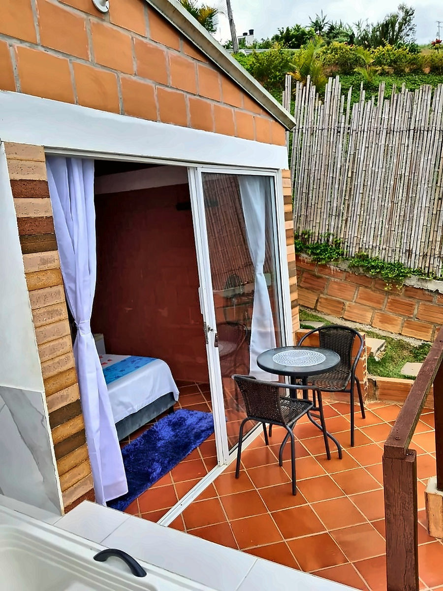 Terraza con mesa para dos frente a la habitación del glamping con jacuzzi