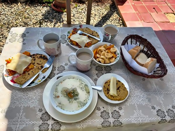 Mesa con caldo, arepas con queso, fruta, pan y café con leche